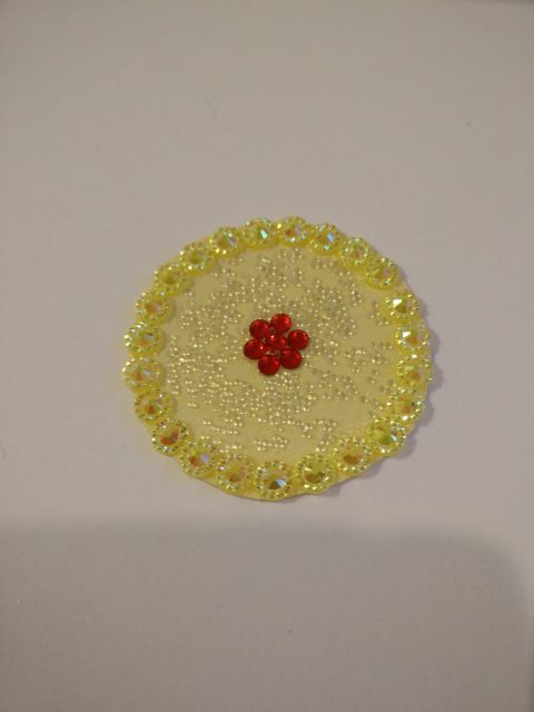 Midtstykket er ferdig med krans av gult bling (ganske diskret synes jeg), et omtrentlig senter av rød bling som en liten blomst og så smurte jeg lim rundt og drysset noe som het "kaviarperler" som er hvite og lett skimrende. Syntes det var passende!
